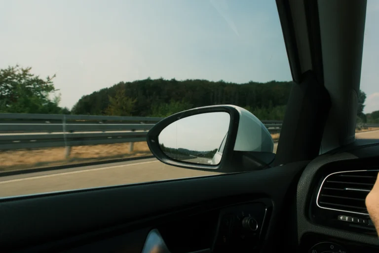 Car side mirror reflecting a highway, illustrating legal tint in PA